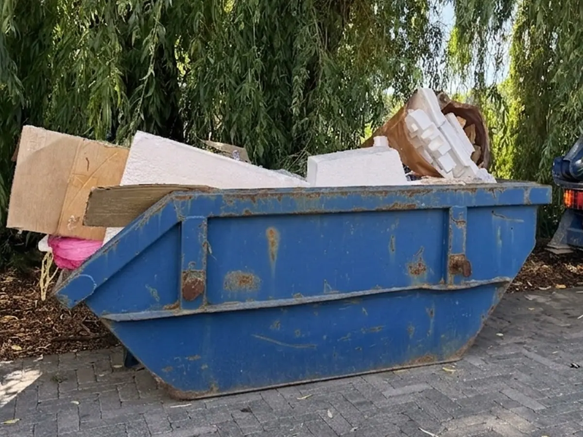 Kontener załadowany kartonami i płytami meblowymi po opróżnianiu domu