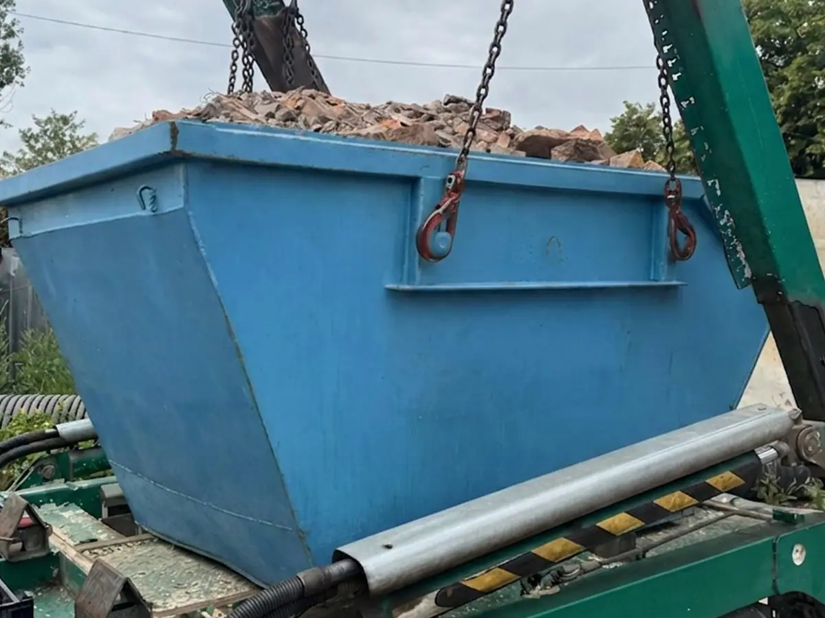 Kontener z gruzem podnoszony na łańcuchach nad samochodem bramowym